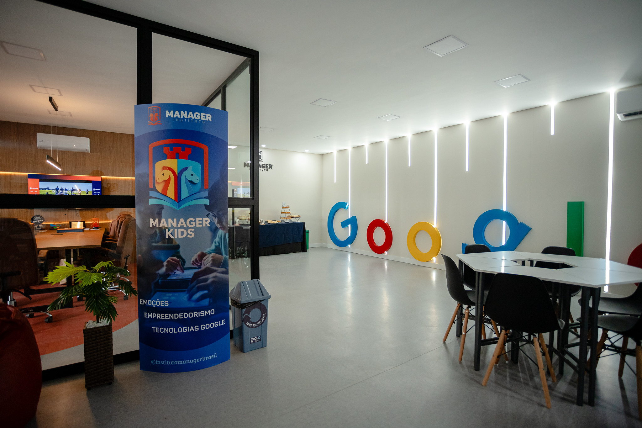 Corredor do instituto com banner Manager Kids e letreiro Google iluminado